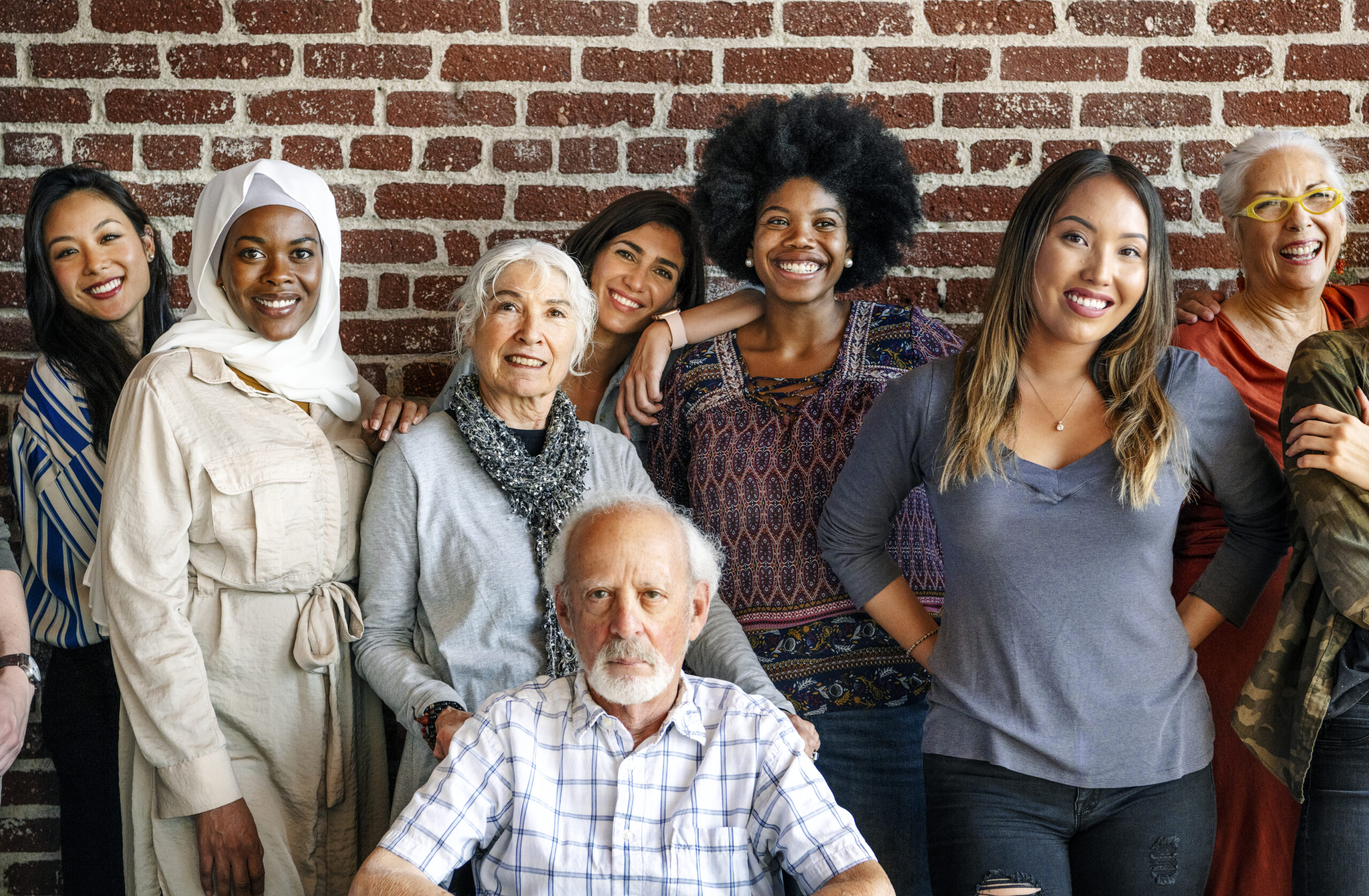 Group of diverse people standing in front of a brick wall Group of diverse people standing in front of a brick wall