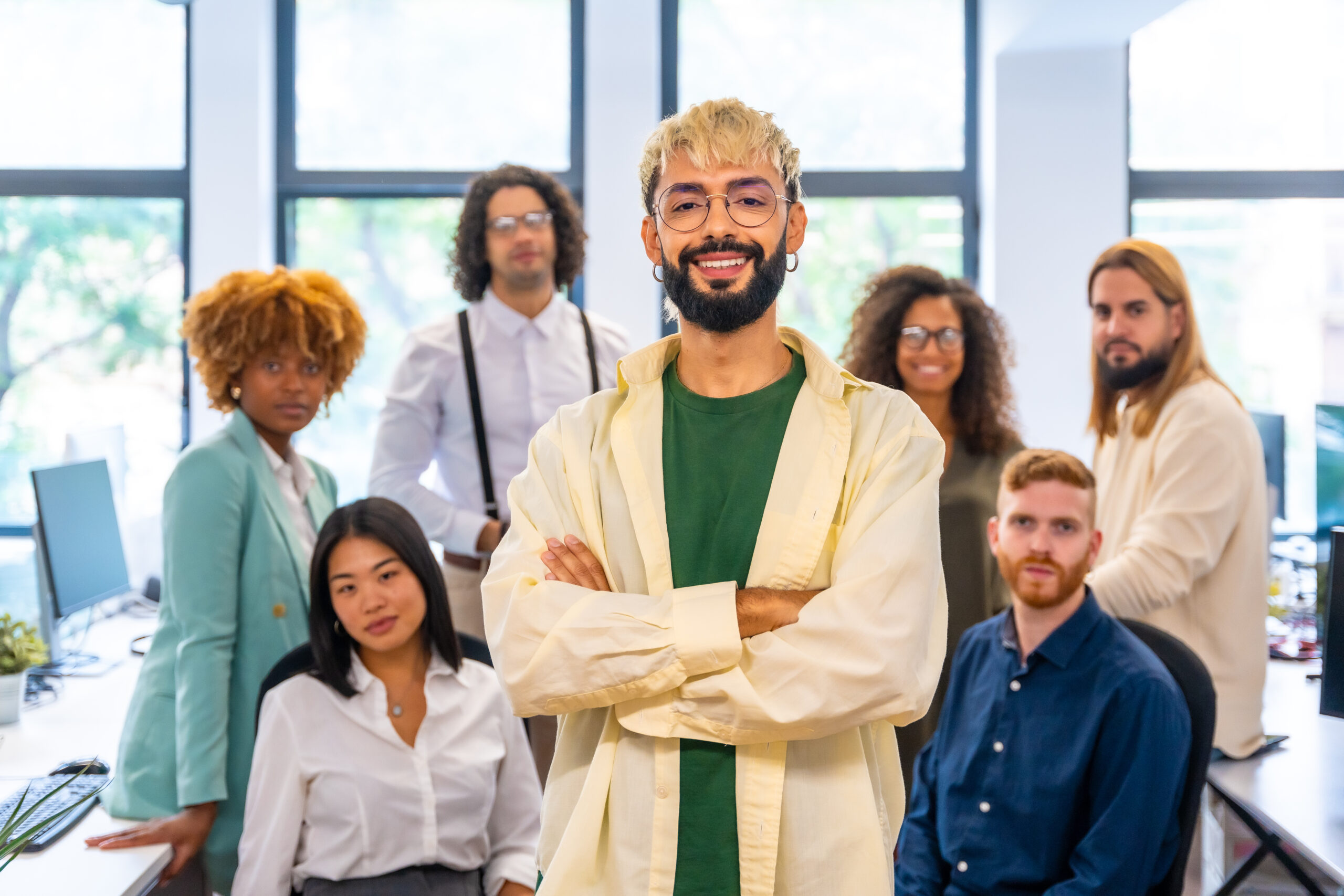 Young and modern entrepreneur smiling at camera next to coworkers Young and modern entrepreneur smiling at camera next to coworkers
